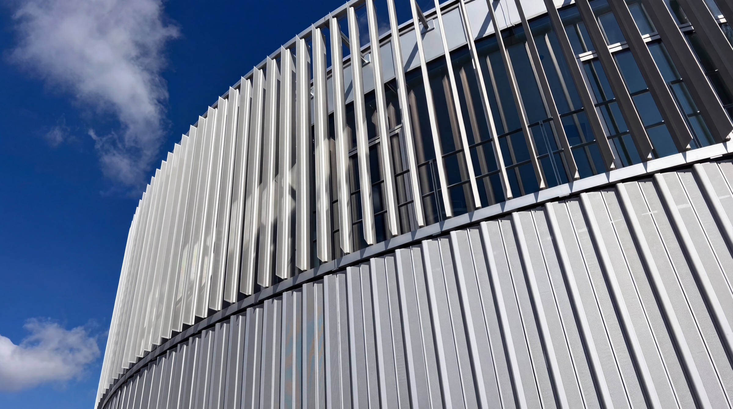 The curved metal facade of the MobiMedia building in Pfarrkirchen against a blue sky